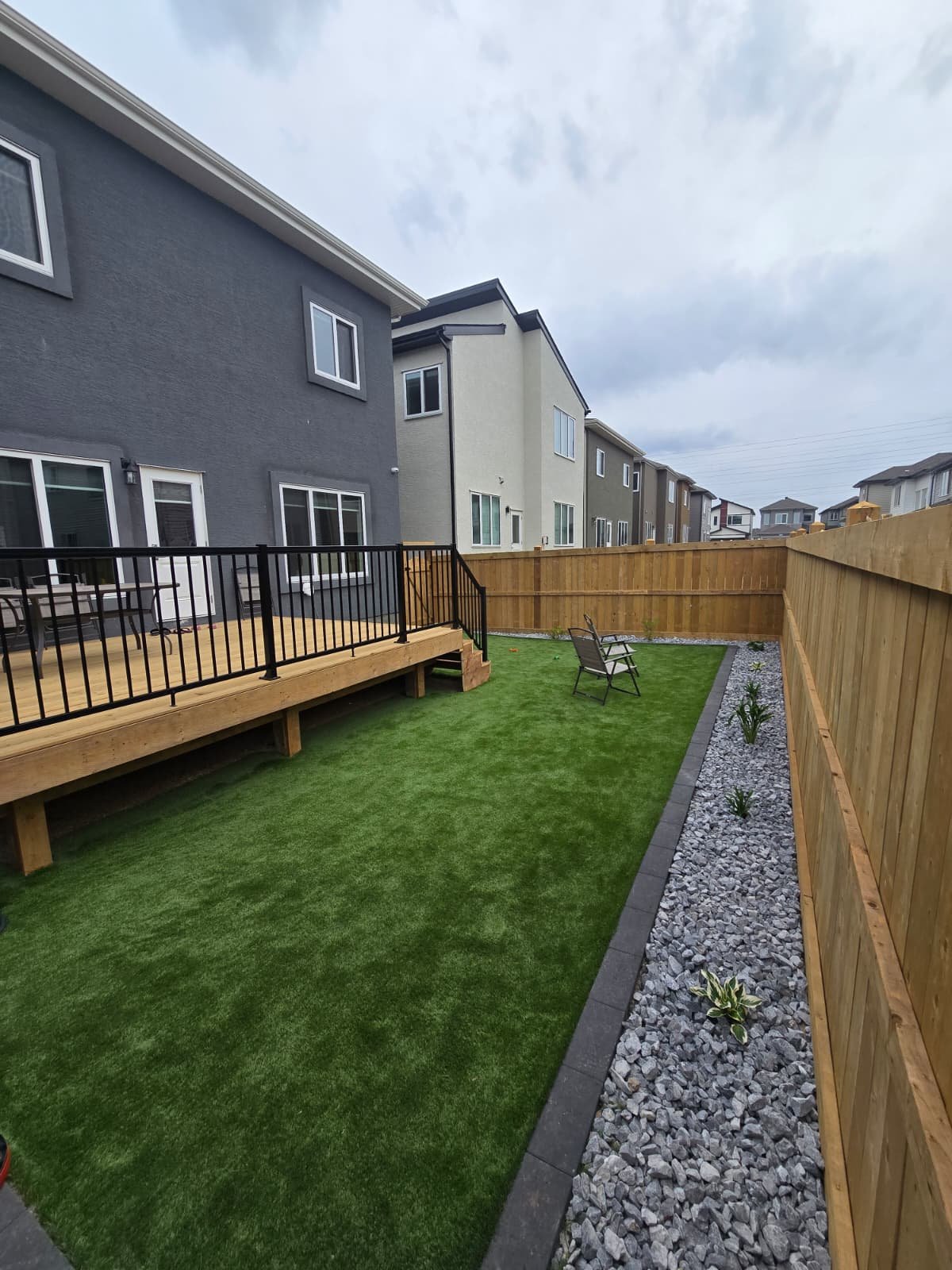 Wood deck with fresh sod and river rock border — Edmonton